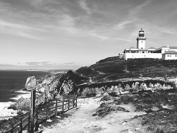 Lighthouse by sea against sky