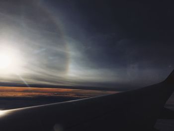 Close-up of airplane wing against sky during sunset