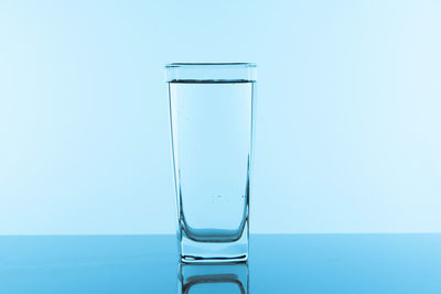 Close-up of glass of water against blue background