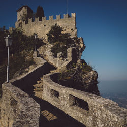 Low angle view of walkway leading towards fortress against clear sky