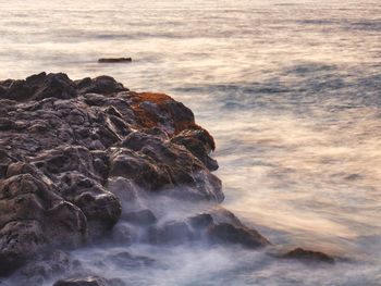 Rock formation on sea shore against sky