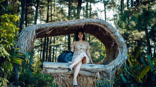 Full length portrait of woman sitting in forest