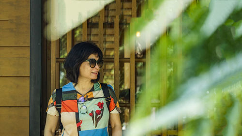 Young woman looking away while standing outdoors