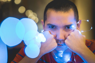 Close-up portrait of young man with illuminated string light