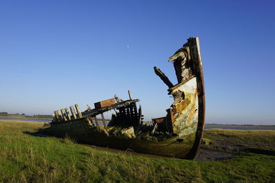 Abandoned truck on field against clear sky