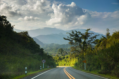 Road by trees against sky