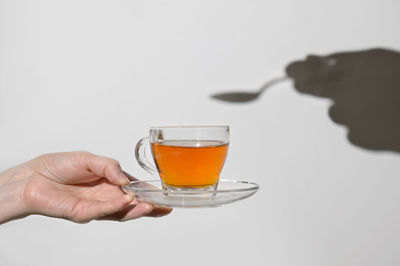 Close-up of hand holding wineglass against white background