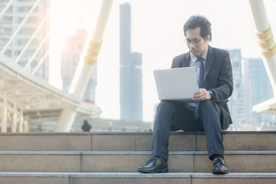 Full length of man sitting on mobile phone