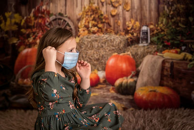 Puts on a medical face mask that protects against the virus. dark autumn background with pumpkins