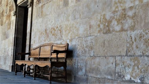 Low angle view of empty bench outside abandoned building