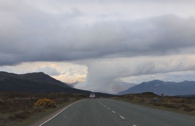 Road leading towards mountains against sky
