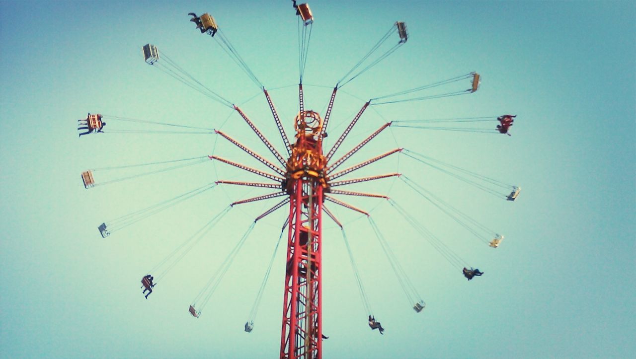 low angle view, amusement park, amusement park ride, arts culture and entertainment, ferris wheel, fun, sky, enjoyment, chain swing ride, leisure activity, clear sky, blue, multi colored, motion, traveling carnival, fairground ride, outdoors, fairground, day, big wheel