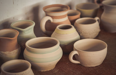 Many clay pot is on the table in pottery. bright pottery. many white, not painted clay pottery ste. 