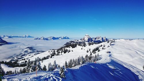 Scenic view of snowcapped mountains against blue sky