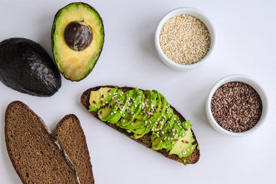 Ingredients for healthy avocado toast. ripe hass avocado, wholegrain bread, sesame flax seeds. vegan