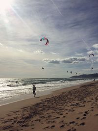 People paragliding at beach against sky