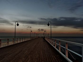 Street by pier against sky during sunset