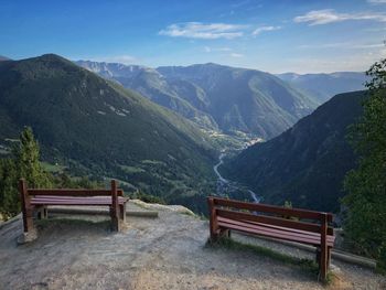 Empty bench on mountains against sky