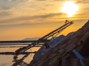 Crane at construction site against sky during sunset