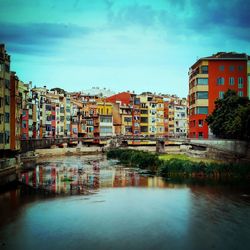 Buildings by river against sky in town