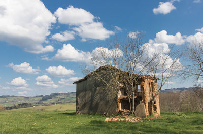 Abandoned house on field against sky