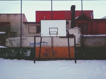 Snow covered houses by building against sky