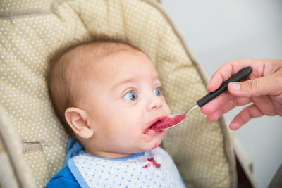 Cropped woman feeding baby boy on baby carriage at home