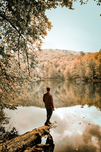 Rear view of man standing by lake against sky