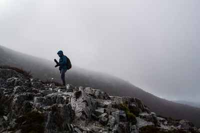 Man standing on rock against mountain during winter