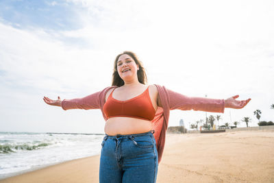 Woman standing at beach against sky