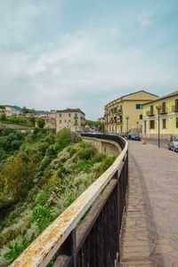 Footpath by buildings against sky