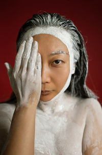 Asian woman with clay mask on face and body