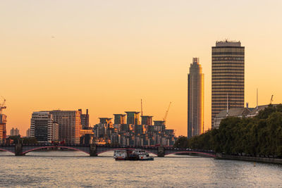 View of river and buildings against sky during sunset