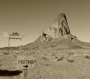 Sign board on rock against sky