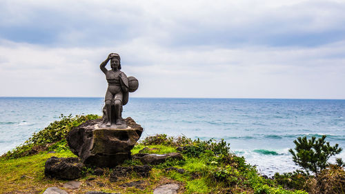 Statue by sea against sky