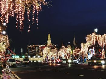 Illuminated city street against sky at night