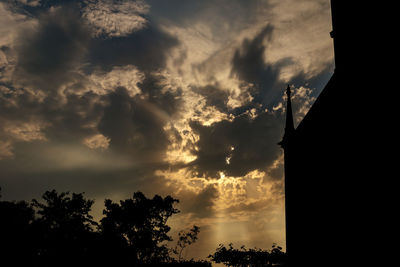 Low angle view of silhouette trees against dramatic sky