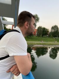 Side view of young man standing by lake