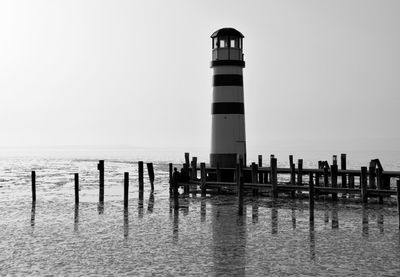 Lighthouse on sea against clear sky