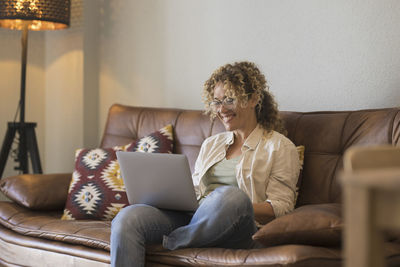 Rear view of woman sitting on sofa at home