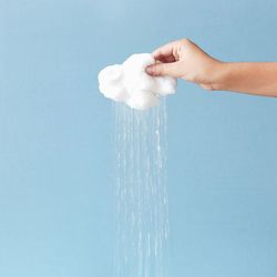 Close-up of hand holding water against sky