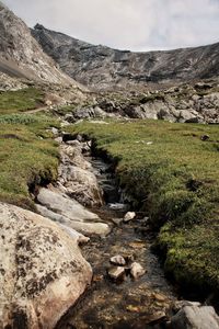 Stream flowing through rocks against sky