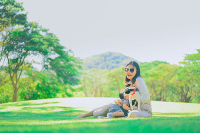 Young woman sitting on land against trees