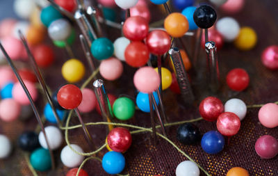 High angle view of colorful beads and metal with thread on fabric