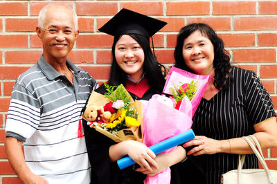 Portrait of family standing against brick wall during convocation