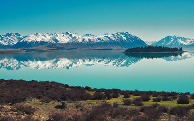 Scenic view of lake and snowcapped mountains against blue sky