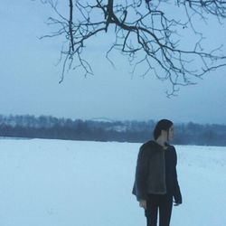 Rear view of man standing by lake against clear sky