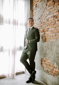 Full length of businessman standing against wall