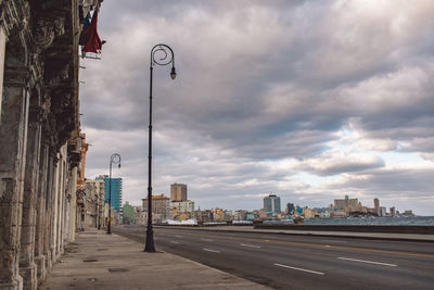 Road by buildings against sky in city