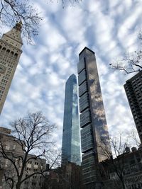 Low angle view of modern buildings against cloudy sky